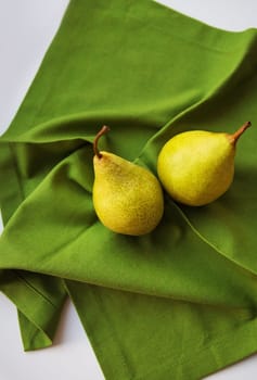 two ripe pear lies on a green napkin.