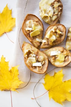 bright pear baked with cheese and nuts on the background of maple leaves.