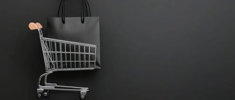 A black shopping cart with a shopping bag against a dark background, featuring copy space. Black Friday sale concept with empty place for text.