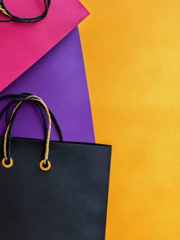 A collection of colorful shopping bags against a vibrant yellow background, offering copy space for text. Black Friday sale concept.