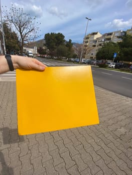 Close up male hand holds yellow envelope in urban city background. Mail, parcels and packages concept