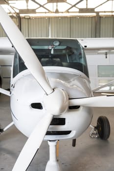Small private lightweight propeller airplane in hangar, closeup photo