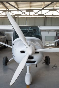 Small private lightweight propeller airplane in hangar, closeup photo