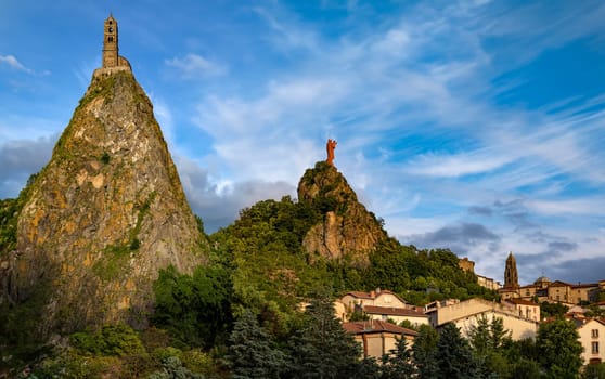 Chapel of St Michel-dAiguilhe and Statue of Notre-Dame de France above the bell tower of Cathedral Nore-Dame in the city of Le Puy-en-Velay in the Auvergne-Rhone-Alpes region of south-central France.