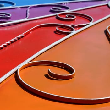 Metal texture of a piece of colored wall with a forged pattern. Rainbow colors
