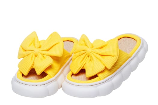 Slippers isolated. Close-up of a pair female yellow soft cosy house slipper with a large bow isolated on a white background, Clipping path. Macro. Womans shoes.