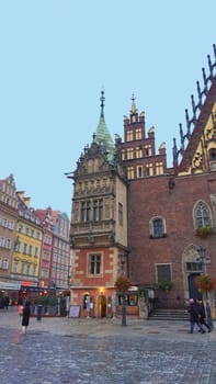 Wroclaw, Poland - April 17, 2022: The people going near old town hall building with a clock in the center of Wroclaw Square at Poland