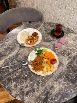 Two plates of diverse cuisine on a marble table, showcasing a combination of colorful vegetables, grains, and meats. an inviting meal setting for a casual dining experience.
