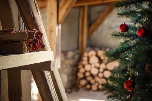 A warm inviting space featuring a Christmas tree adorned with ornaments and a stack of firewood in the background enhancing the holiday spirit.