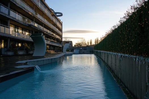 A serene view of a modern pool at sunset with elegant architecture and lush greenery adorning the surrounding area perfect for relaxation.