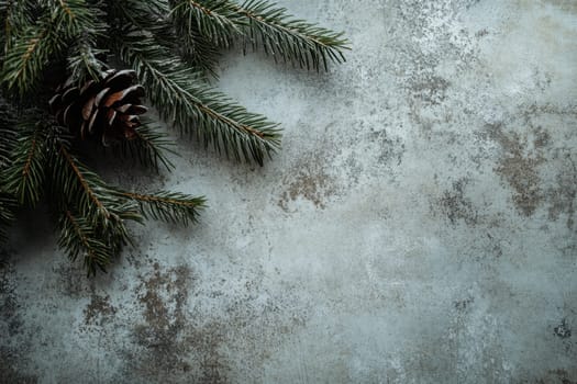 Fresh pine branches with a decorative cone rest on a textured gray background evoking a serene winter atmosphere.