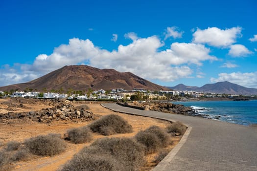 View of the vacation region at Playa Blanca and the promenade with volcanic landscape in the background