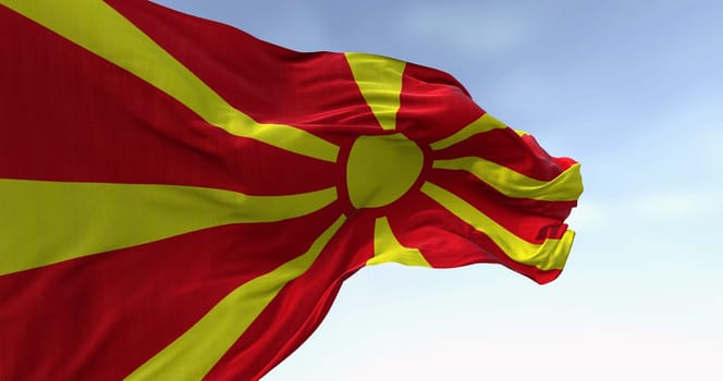 North Macedonia national flag waving in the wind on a clear day. Stylized yellow sun with eight rays extending to the edges of a red field. 3d illustration render. Fluttering fabric.