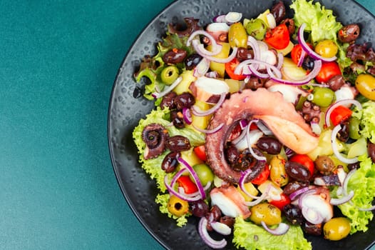A plate of octopus salad with herbs, potatoes and olives. Free space for your text. Long banner