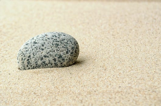 Single stone on beach sand with customizable space for text or ideas.