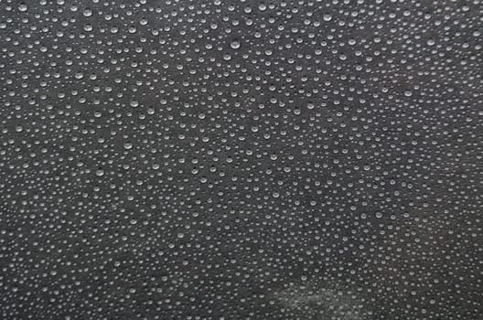 Small rain droplets on dark cover background.