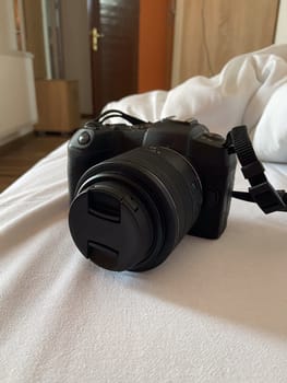 Digital camera rests on a white bed, ready for use, symbolizing creativity and exploration. Relaxed setting suggests a moment of pause before capturing new memories and experiences.
