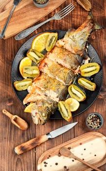Whole trout fish baked in an oven with kiwi. Space for text.