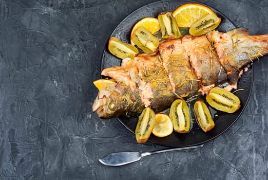 Whole trout fish baked in an oven with kiwi. Space for text.