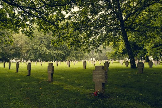 Bastogne, Belgium - July 17 2021: German war graves resting peacefully under green trees at the Recogne war cemetery in Bastogne, Belgium. Battle of the Bulge