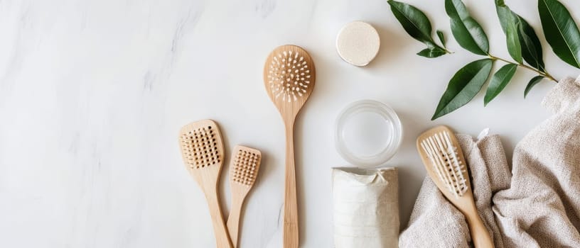 Flat lay of sustainable bamboo bathroom accessories including brushes, soap, and towel with green leaves, showcasing eco friendly personal care products.