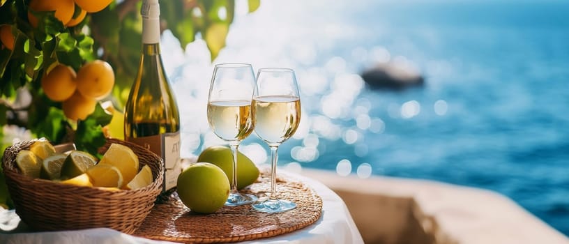 Two glasses of white wine with bottle, citrus fruits, and scenic ocean view, perfect setting for a romantic beach date or vacation.