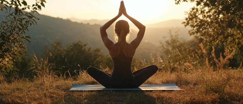 Silhouette of a woman in lotus pose practicing yoga outdoors during golden hour, surrounded by lush nature and mountain scenery.