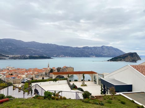 Coastal town with terracotta rooftops stretches along the serene blue waters, framed by majestic mountains. Tranquil landscape creates a perfect harmony between architecture and nature, offering a stunning view.