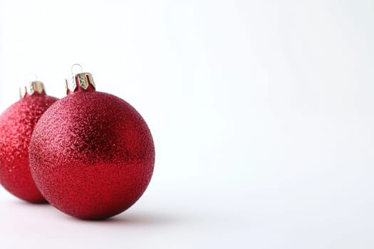 Two shimmering red Christmas ornaments rest against a white background perfect for holiday decoration and seasonal festivities.