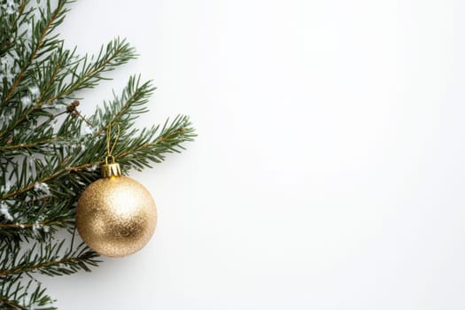 A gold ornament dangles from a snow dusted pine branch creating a festive atmosphere for the holiday season.