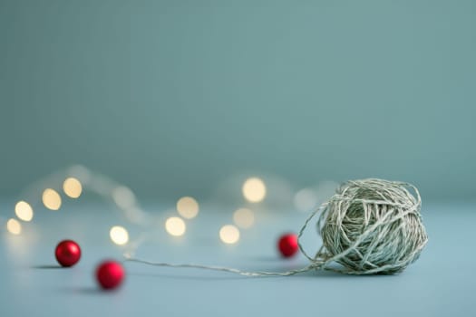 Twine is intertwined with red ornaments and warm lights creating a cozy crafting atmosphere during the holiday season.