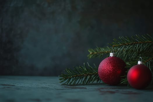Two red ornaments rest beside pine branches on a dark surface creating a cozy holiday atmosphere perfect for Christmas decoration.
