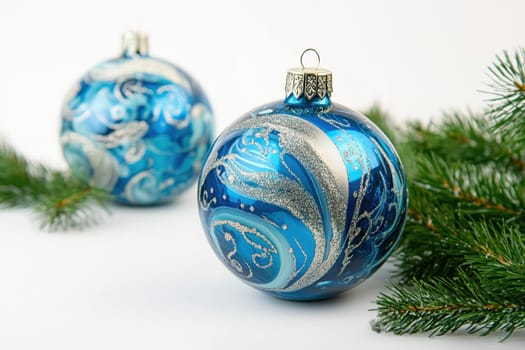 Two elegant blue Christmas ornaments sit among evergreen branches showcasing intricate silver patterns that reflect festive spirit.