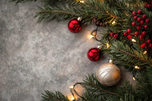 A festive arrangement featuring green pine branches adorned with red and gold ornaments surrounded by warm string lights.