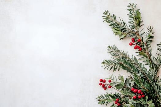 A close up of evergreen branches adorned with bright red berries set against a light neutral background perfect for holiday decor.