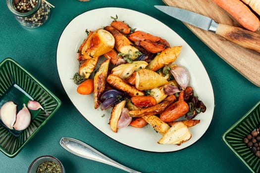 Roasted root vegetables, baked parsnip root, red onions, carrots, and garlic for a vegan dish.