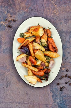 Roasted root vegetables, baked parsnip root, red onions, carrots, and garlic for a vegan dish.
