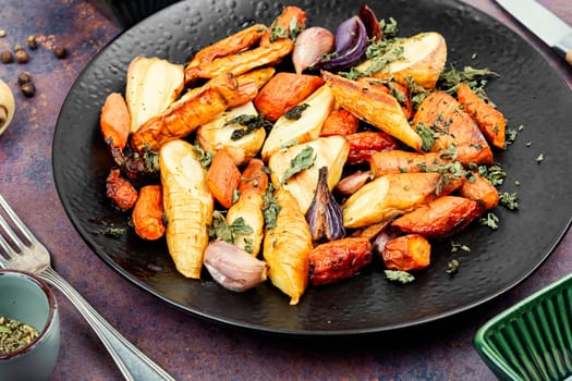 Roasted root vegetables, baked parsnip root, red onions, carrots, and garlic for a vegan dish.