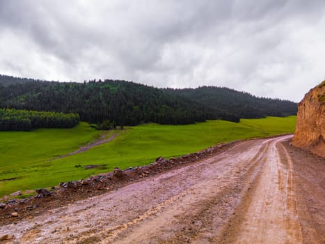 dirt road in the mountain hills at rainy summer day in Kyrgyzstan