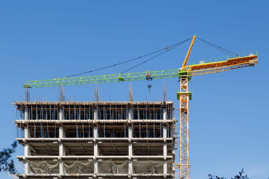 A contemporary construction site showcasing a large tower crane and the building framework set against a clear blue sky