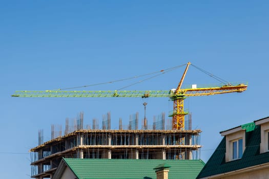 A contemporary construction site showcasing a large tower crane and the building framework set against a clear blue sky
