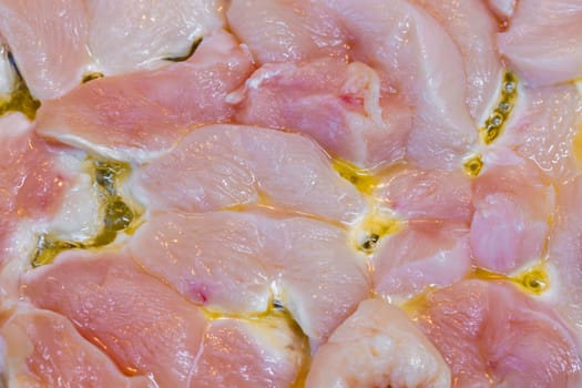 closeup full-frame background of raw chicken breast meat just starting to roast.