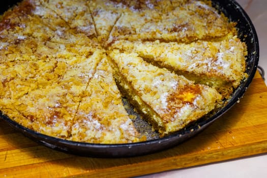 domestic apple pie in a black round cast iron pan sliced into sectors, closeup