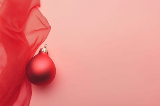 A vibrant red ornament rests beside flowing red fabric capturing the essence of festive holiday decor and warmth.