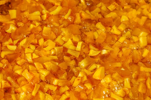 full-frame background and texture of sliced yellow apples soaking in syrup during confiture cooking.