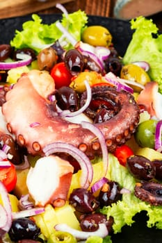 Appetizing salad of octopus, potatoes, olives and greens. Copy space.