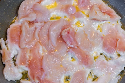 closeup full-frame background of raw chicken breast meat just starting to roast.