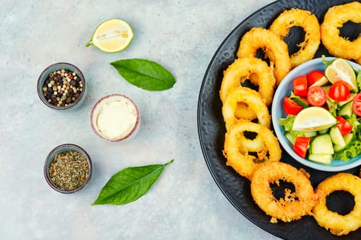 Calamari, fried squid rings with raw vegetable salad. Rustic style.