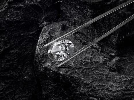 Cut Beautiful diamond held by tweezers on black coal background