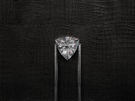 Cut Beautiful diamond held by tweezers, on a black leather background